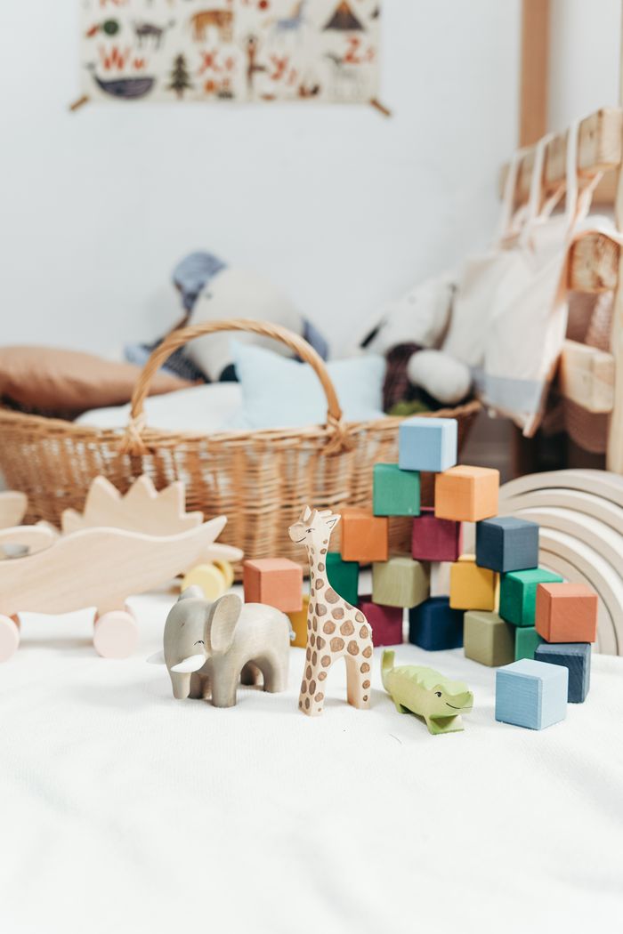 Services Cozy bedroom featuring a collection of colorful wooden toys and wicker basket, perfect for family fun.