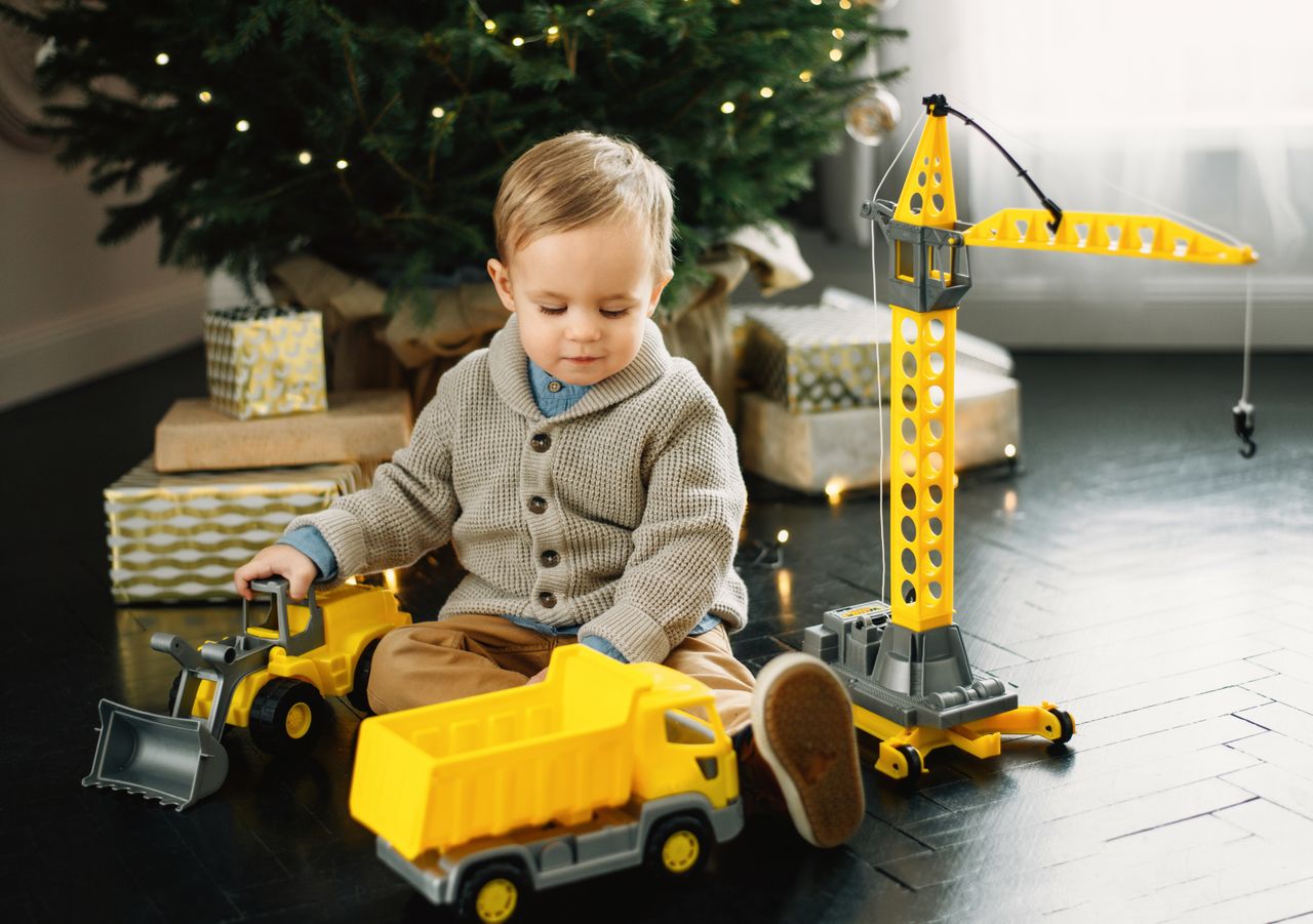 The Art of Drawing Readers In: Your attractive post title goes here A young boy plays with toy trucks and a crane under the Christmas tree.